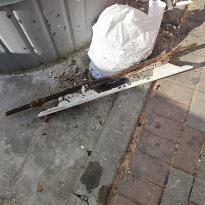 פסולת בנייה על המדרכה ליד פח ירוק