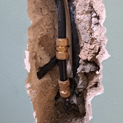 צינור שחור עם מחבר מתכת בקיר פתוח