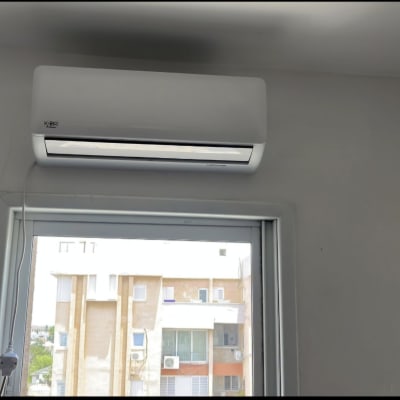 מזגן מותקן על קיר מעל חלון עם כבל חשמל