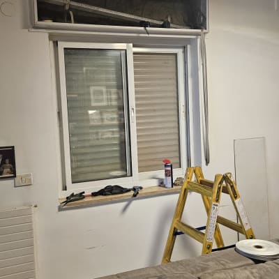 חלון עם תריסים, סולם וכלים על אדן החלון