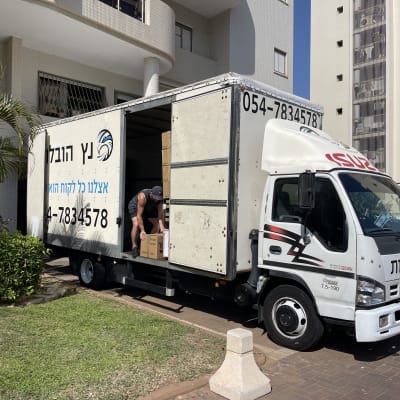 אדם מעמיס קרטונים למשאית הובלה פתוחה