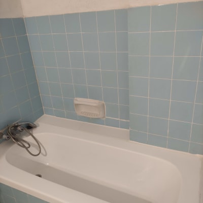 אמבטיה עם חיפוי אריחים כחולים וברז מקלחת