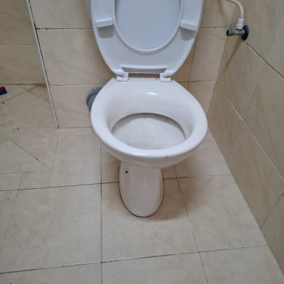 אסלה לבנה עם מכסה פתוח וצינור מים