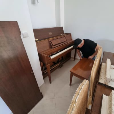 פסנתר עומד פתוח עם אדם מתכופף לידו