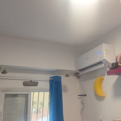 מזגן מותקן על קיר לבן עם אור כחול דולק