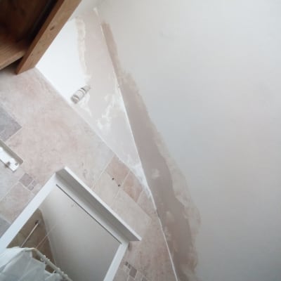 קיר עם תיקוני צבע וטיח, מברשת צבע על הרצפה