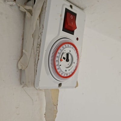 שעון טיימר חשמלי עם מתג אדום על קיר