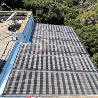 גג עם לוחות מתכת ומזגן על רקע עצים