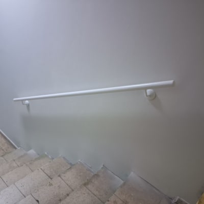 מעקה לבן מותקן על קיר מעל מדרגות