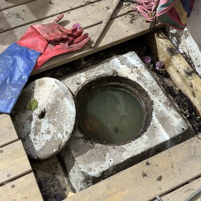 פתח ביוב פתוח עם כפפות וכלי עבודה