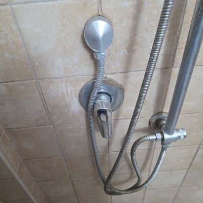 ברז מקלחת עם צינור מתכת על קיר אריחים