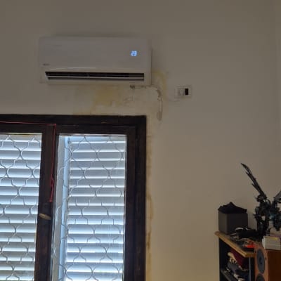 מזגן מותקן על קיר מעל חלון עם סורגים