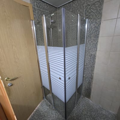 מקלחון זכוכית עם דלתות מתכת בחדר אמבטיה