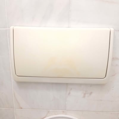 לחצן הדחה של אסלה על קיר אריחים