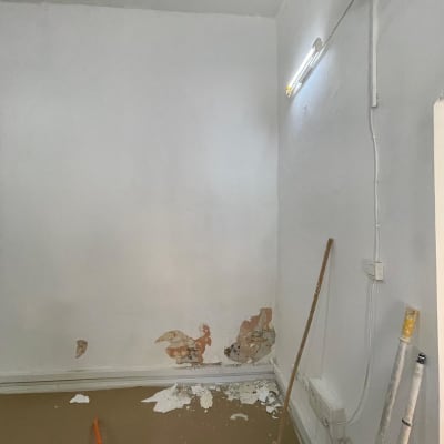 קיר עם קילופי צבע, מטאטא ומוט צביעה