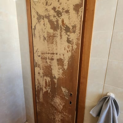 דלת עץ עם צבע מתקלף בחדר אמבטיה