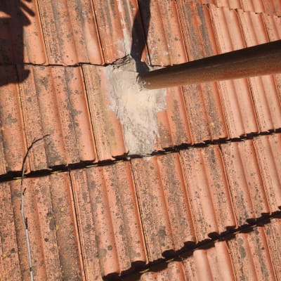 צינור מתכת עובר דרך רעפים עם תיקון בטון