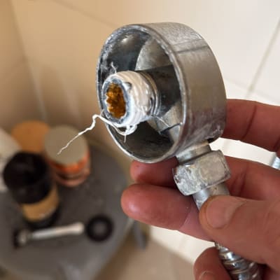 חיבור צינור מתכת עם סרט טפלון ביד של אדם