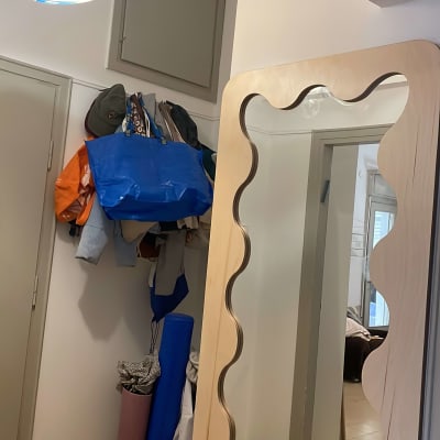 מראה עם מסגרת עץ, שקיות ובגדים תלויים על הקיר