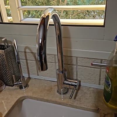 ברז נירוסטה בכיור מטבח עם חלון ברקע