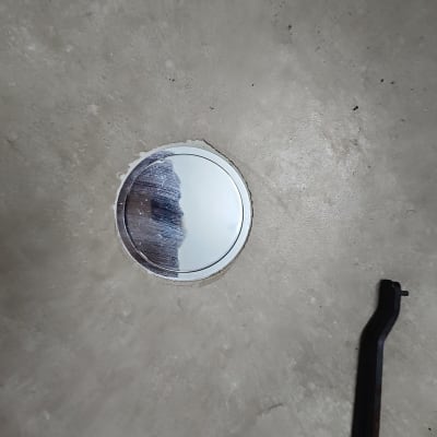 פתח ניקוז עגול על רצפה עם כלי עבודה שחור