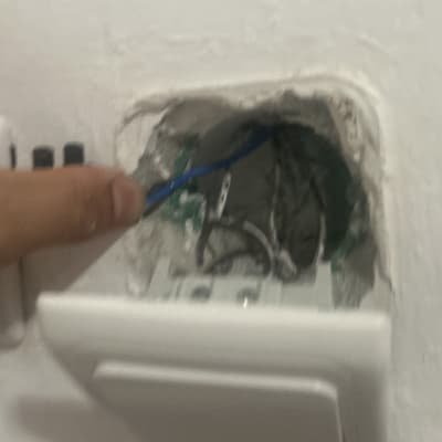 חיווט חשמלי בקיר עם יד מחזיקה כבל כחול