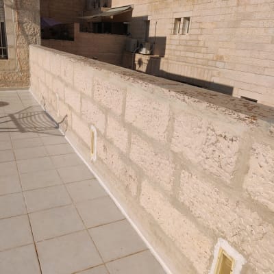 קיר אבן עם איטום לבן לאורך החיבור לרצפה