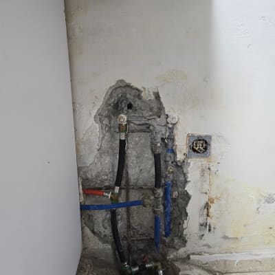 צינורות מים חשופים בקיר עם סימני רטיבות