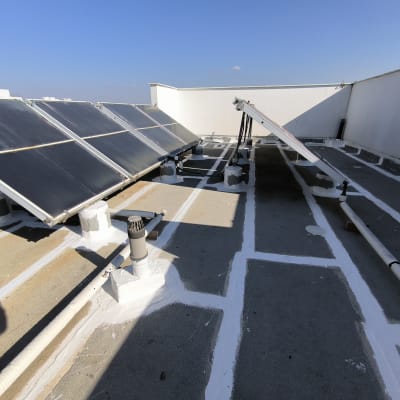 איטום גג עם חומר לבן סביב צינורות וקולטים