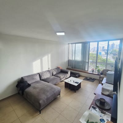 סלון עם ספה, שולחן ומרפסת עם נוף עירוני