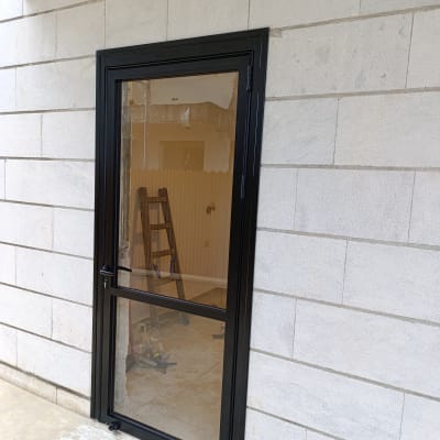 דלת אלומיניום שחורה מותקנת בקיר בטון