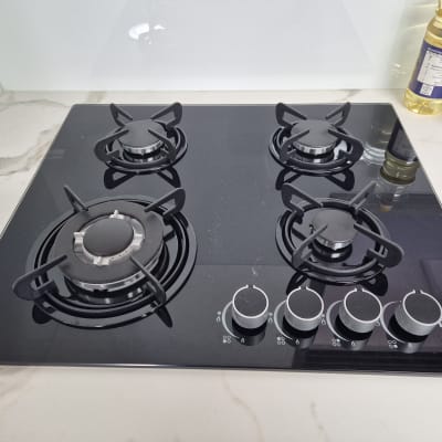 כיריים גז שחורות עם ארבעה מבערים וכפתורי שליטה