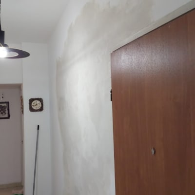 קיר עם תיקוני טיח, מטאטא ומגב על הרצפה