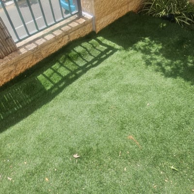 דשא סינתטי ליד גדר אבן ועץ