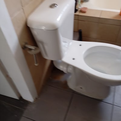 אסלה לבנה עם מיכל הדחה בחדר אמבטיה