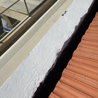 גג עם רעפים כתומים וציפוי לבן על הקצה