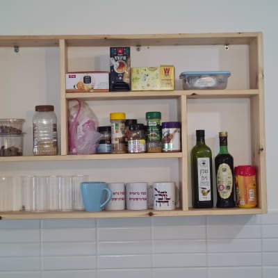 מדף עץ עם תבלינים, כוסות ושמן זית