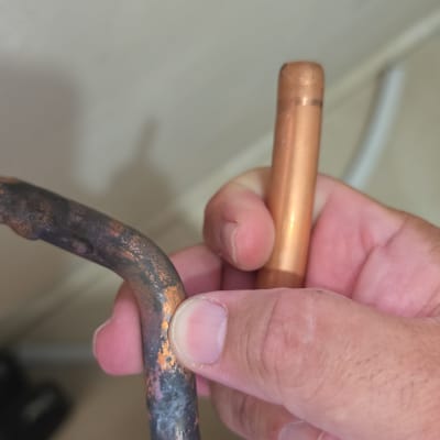 יד מחזיקה צינור נחושת עם סימני חלודה