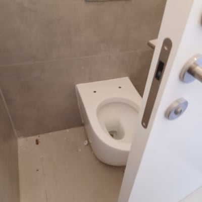 אסלה תלויה וחיפוי קיר אפור בחדר שירותים משופץ