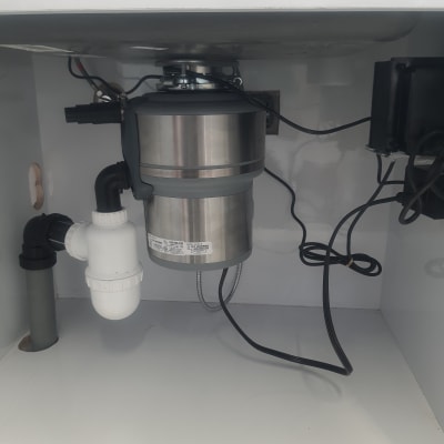 מתקן טוחן אשפה מתחת לכיור עם צינורות וחיבורים