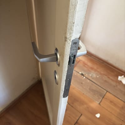 דלת עם מנעול וידית מתכת על רצפת עץ