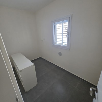 חדר צבוע עם קירות לבנים ורצפת אריחים אפורה