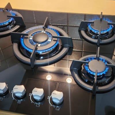 כיריים גז עם חמש להבות כחולות ומתגים לבנים