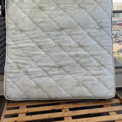 מזרן עומד על מסגרת עץ, עטוף בניילון שחור