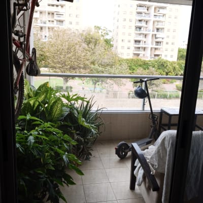 מבט למרפסת מרוהטת ומוצלת דרך פתח דלת הזזה