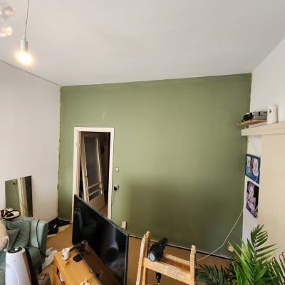 קיר צבוע בירוק עם סולם וחפצים לצביעה