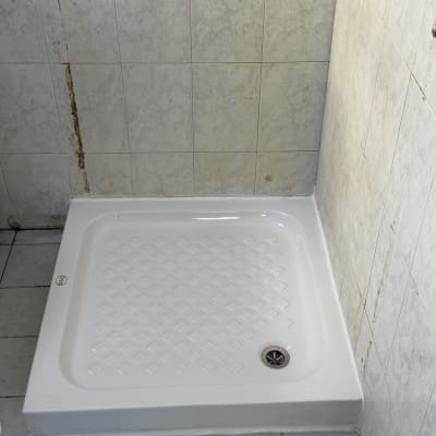 מקלחת עם אריחים לבנים וקירות מתקלפים
