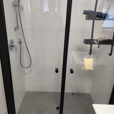 מקלחון עם דלתות זכוכית ומדף לאביזרים