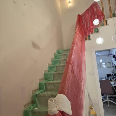 מדרגות מכוסות בניילון ירוק ואדום לשיפוץ
