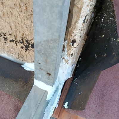 איטום גג עם חומר לבן סביב מתכת וקיר